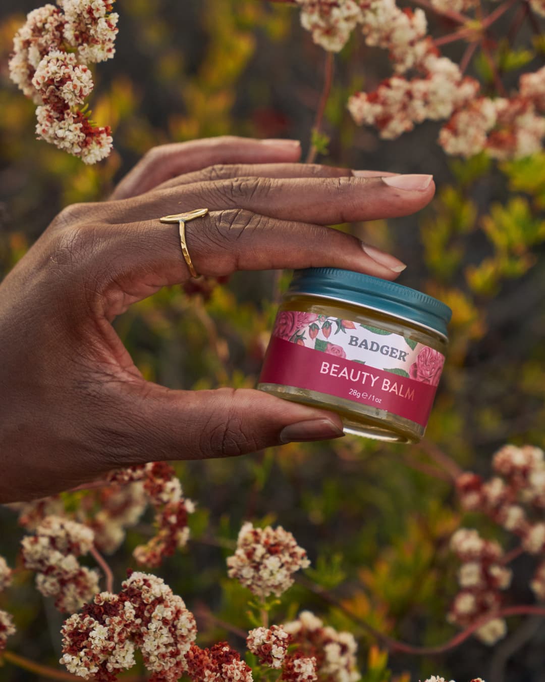 Badger Beauty Balm held among wildflowers — natural skincare product photography | Black Rabbit Creative