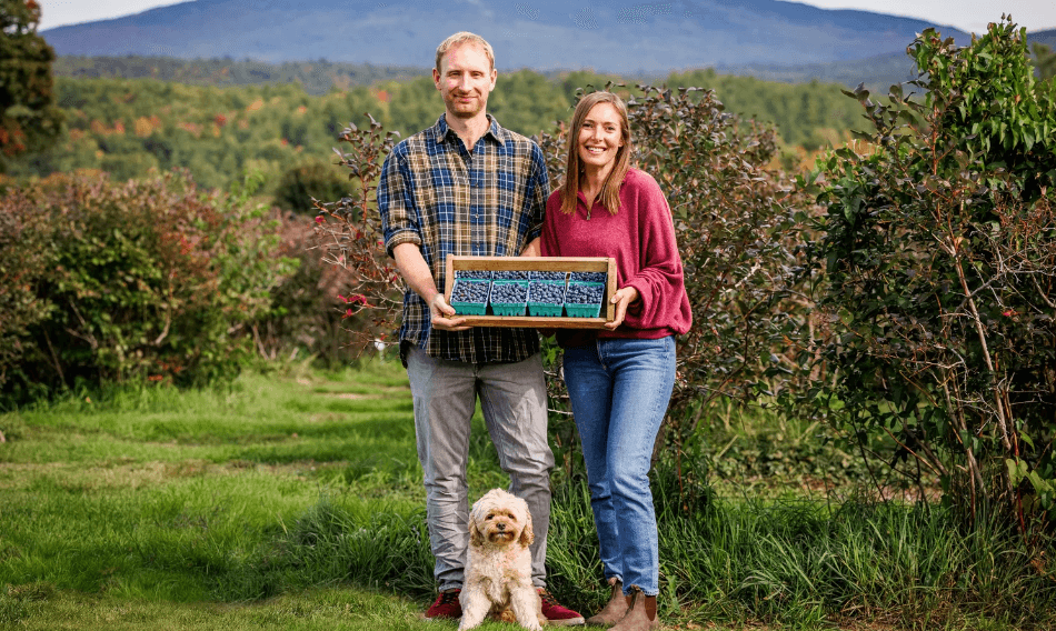 Oliver and Elise, owners of Monadnock Berries, standing in front of Mount Monadnock holding their farm sign — legacy berry farm brand identity by Black Rabbit Creative