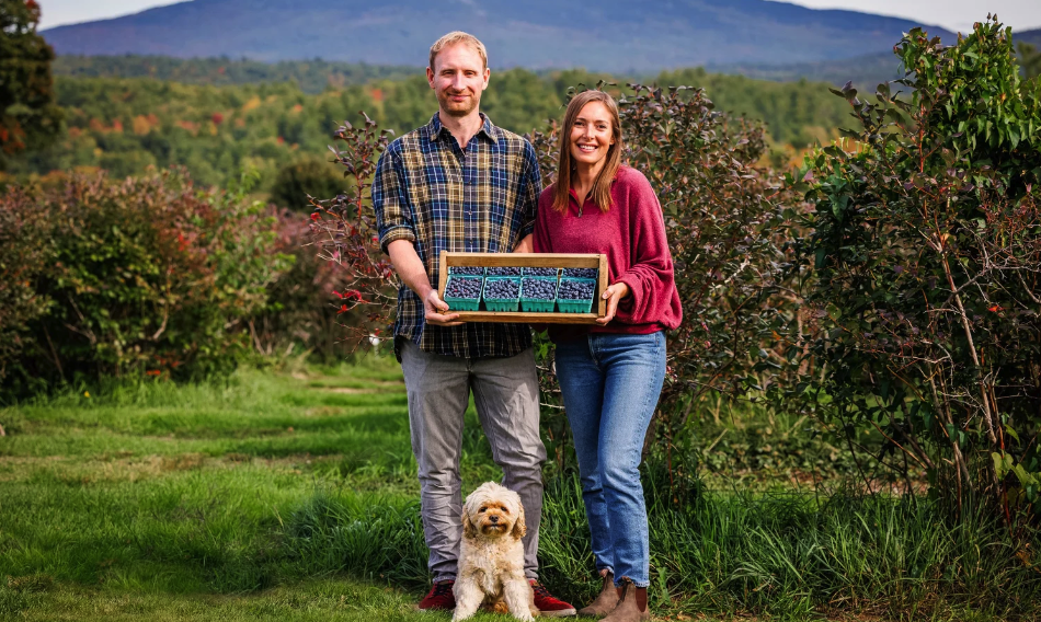 Oliver and Elise, owners of Monadnock Berries, standing in front of Mount Monadnock holding their farm sign — legacy berry farm brand identity by Black Rabbit Creative, Portsmouth NH, New Hampshire, New England